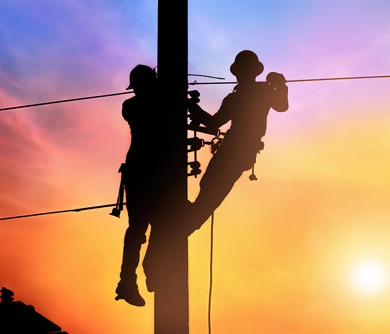 Workers on pole at sunset